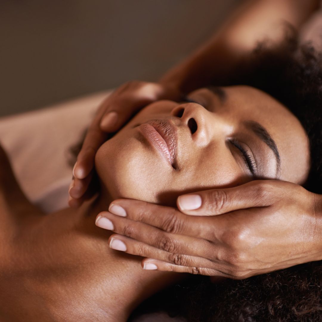 A close up of a woman performing a beauty treatment on a client's face. 