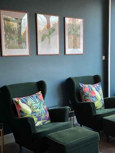 A portrait image of two plush royal green velvet wingback pedicure chairs in Luminis Blackheath.