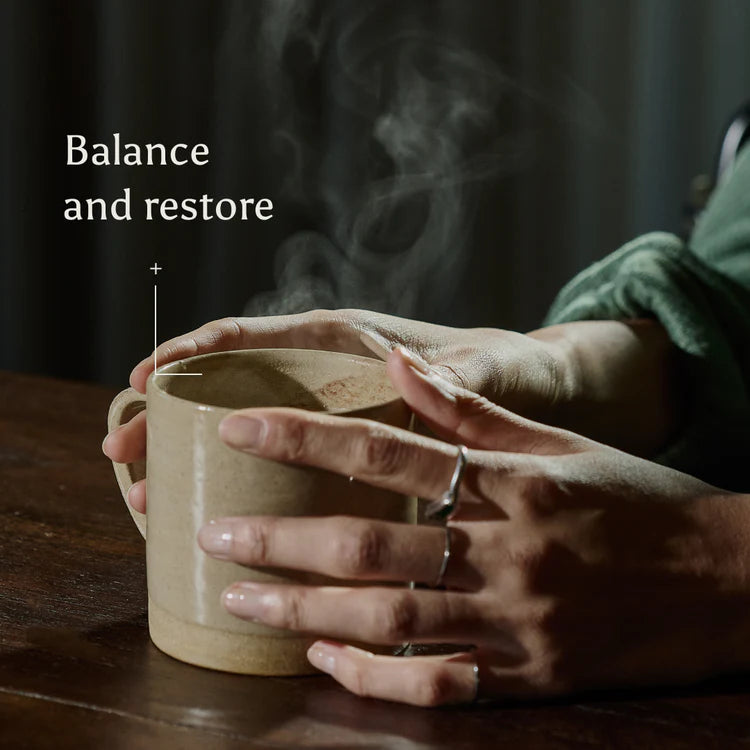 Person holding a steaming mug with text &