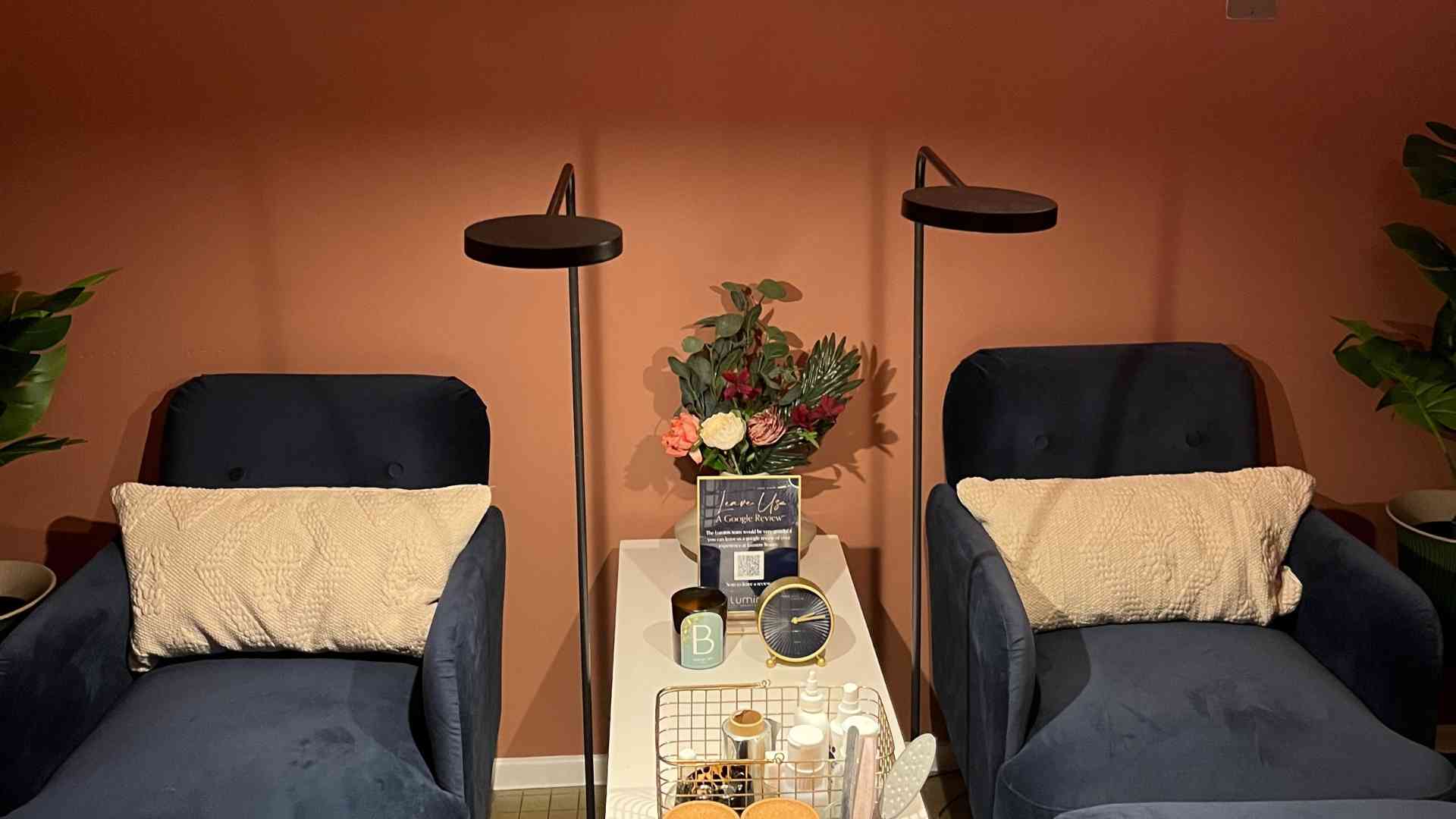 Two navy velvet plush chaise lounges for pedicures in a Luminis Canary Wharf with terracotta painted walls. 