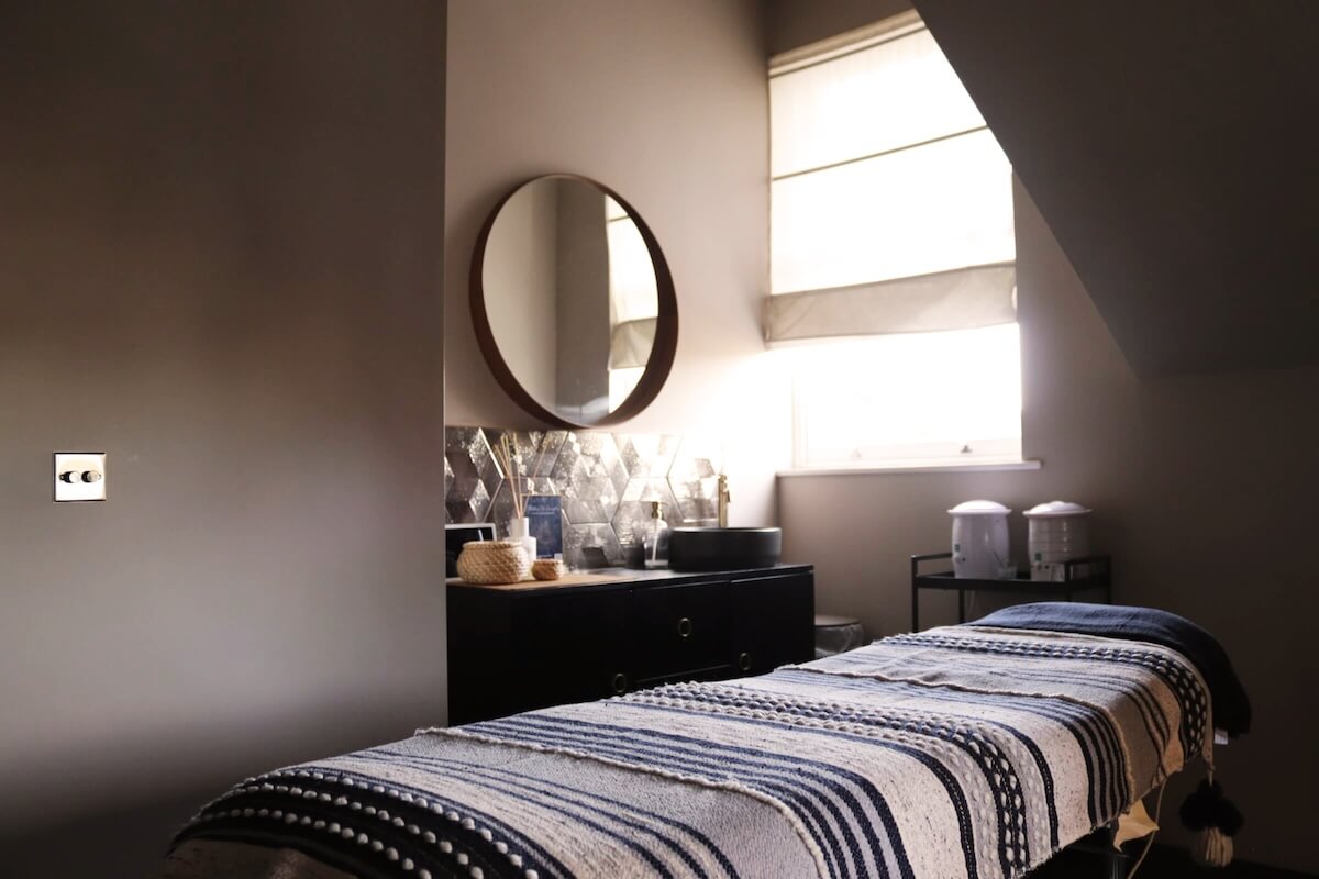 Modern beauty treatment room with patterned boho towelling on massage bed.