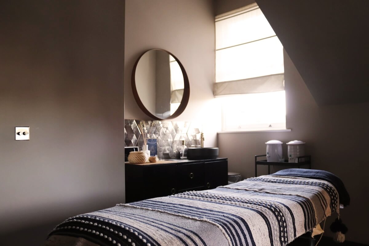 Modern beauty treatment room with patterned boho towelling on massage bed. 