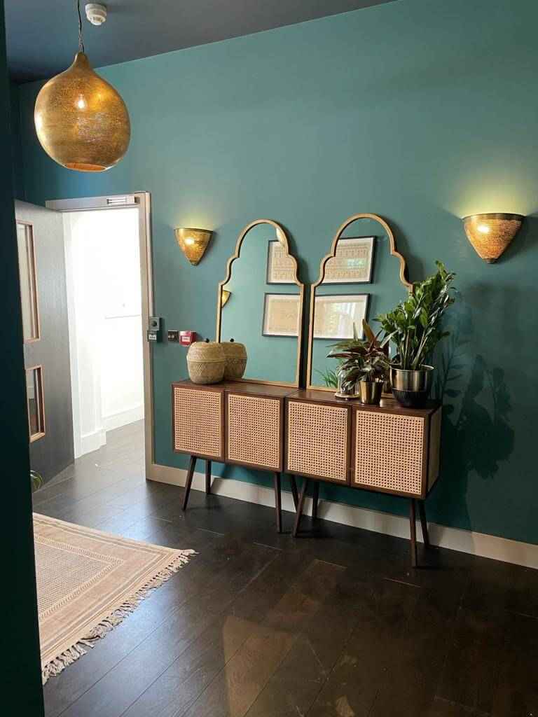 Two Morroccon inspired mirrors on a rattan side bench in the waiting room of a beauty salon with ambient lighting.