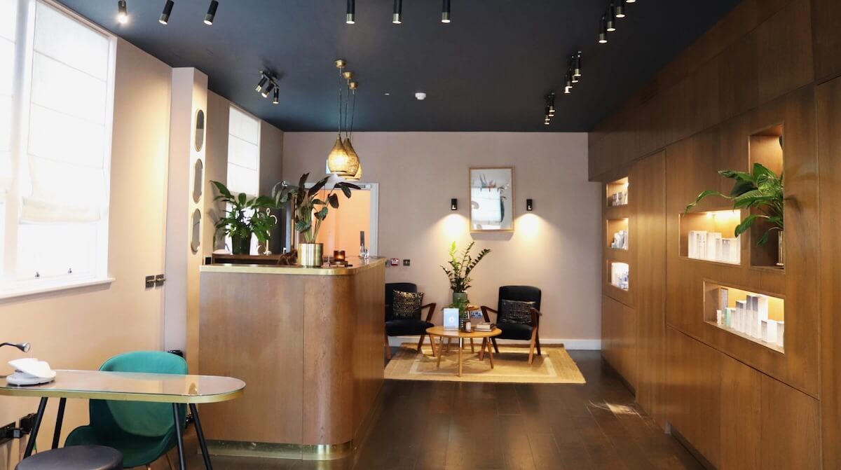 Luminis Chiswick's reception featuring modern wooden flooring and cupboards, plants and a seating area.