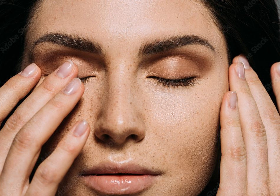 A close up of a woman showcasing her face after an receiving eyelash and eyebrow treatments.