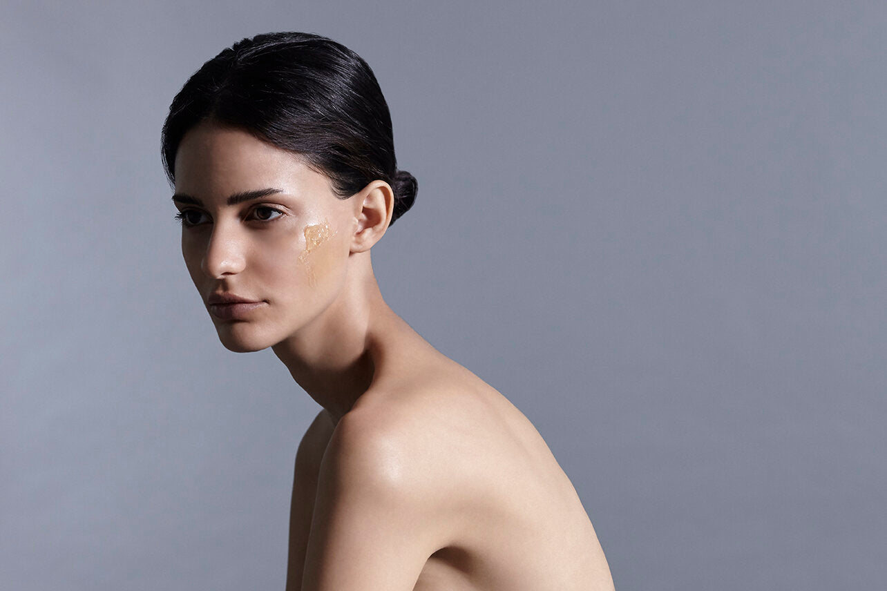 A landscape shot of a model facing side on with a hydrating serum showcased on her cheek.