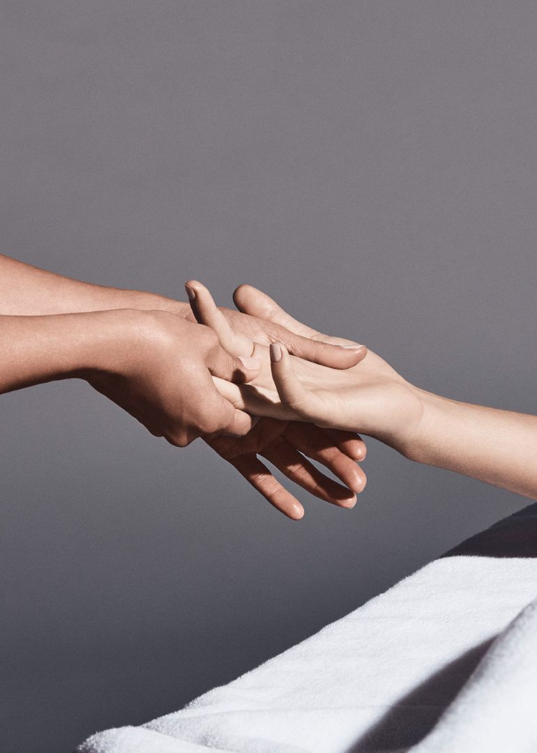 A close up of a person's hands reaching out and holding onto another persons hand. .