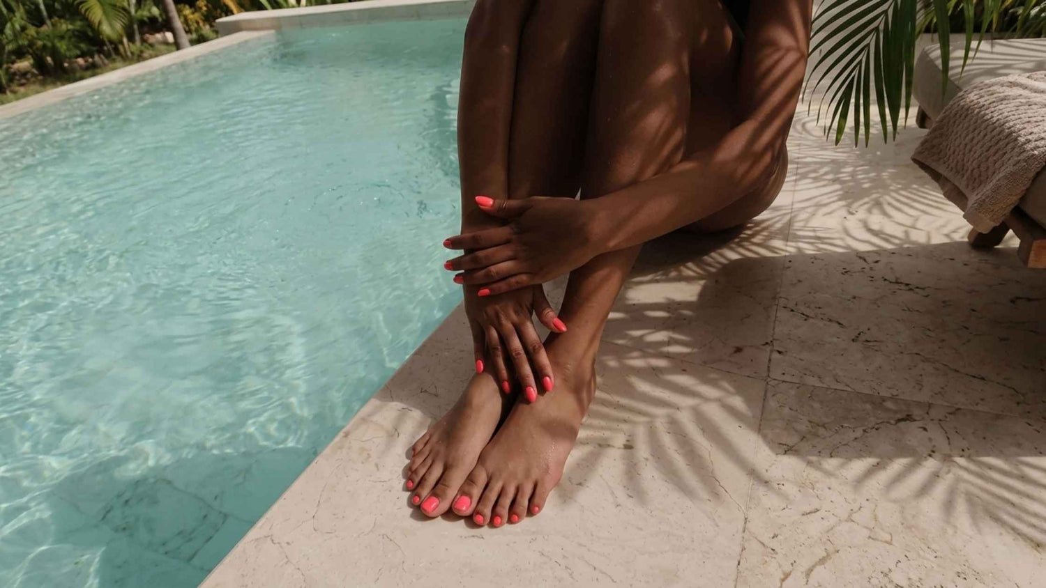 A woman with a coral pedicure and manicure sat by the pool