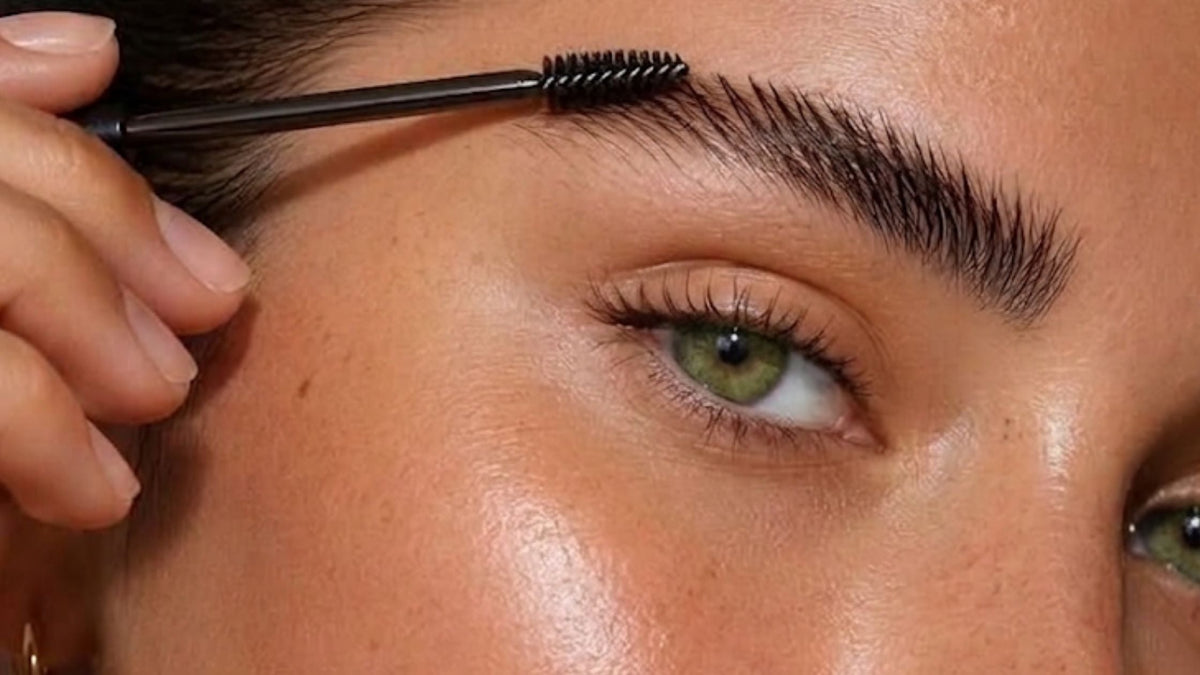 Beauty therapist shaping and brushing a client's eyebrows