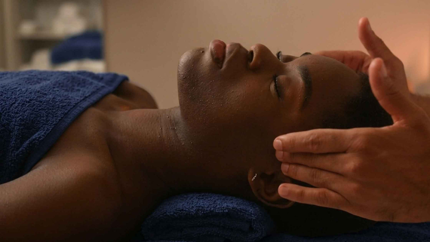 A woman receiving a massage on her temples in a spa setting