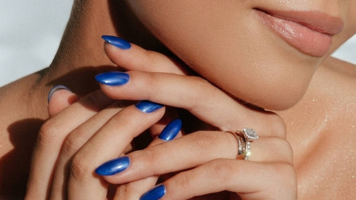 A woman holding her blue, manicured nails near to her face