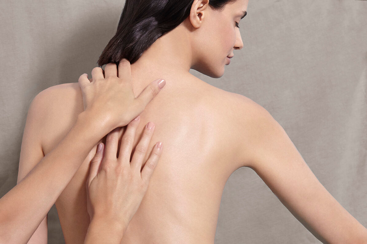A female model's back with two hands massaging her back. 