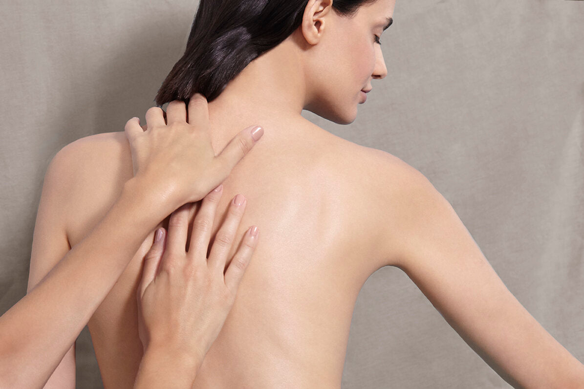 A female model's back with two hands massaging her back. 