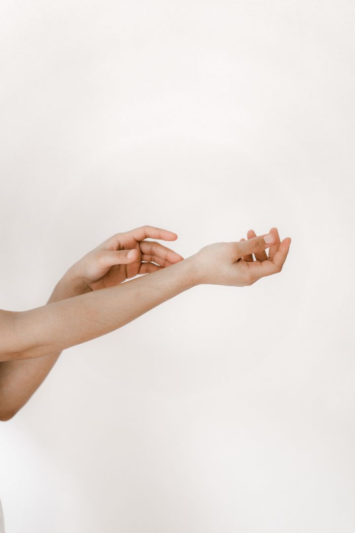 A person's arms reaching out into the distance with a plain white background. 