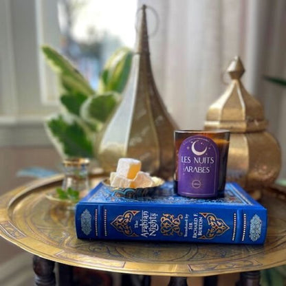 A product shot of the Les Nuits Arabes Candle surrounded but Turkish inspired gold lanterns.  