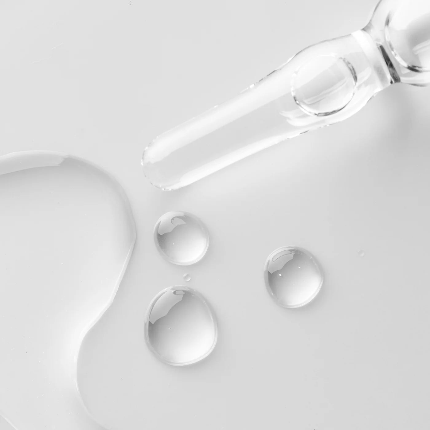 Close-up of a dropper with clear liquid on a light gray background