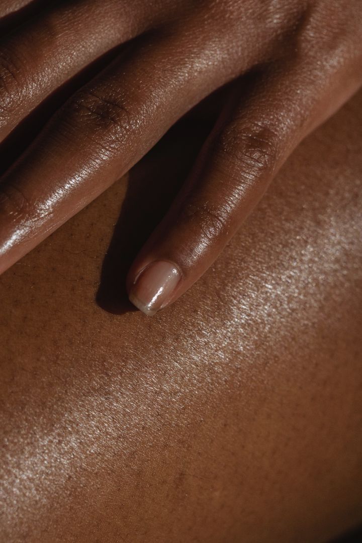 A close up of a person's smooth, hairless legs and manicured nails holding the leg. 