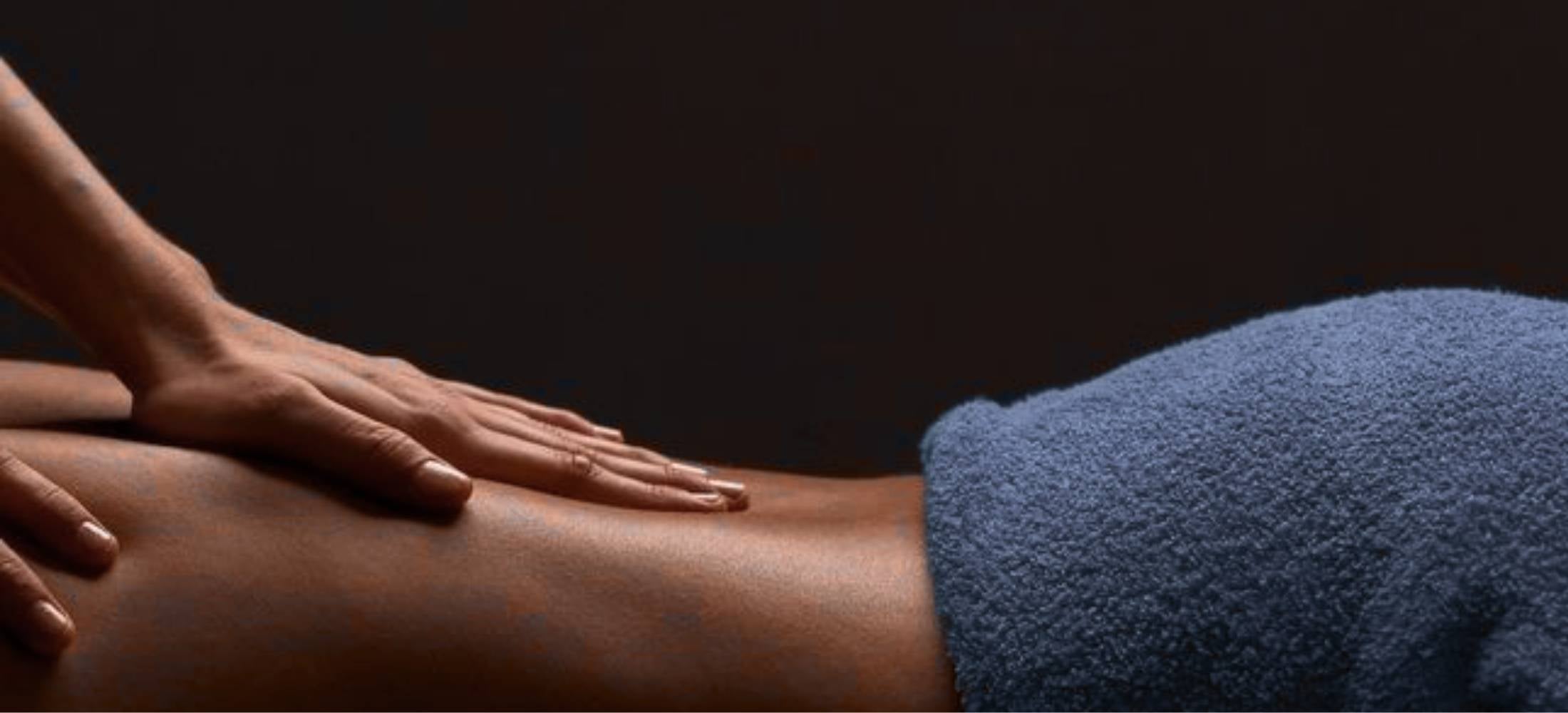 Person receiving a massage with a blue towel on a dark background