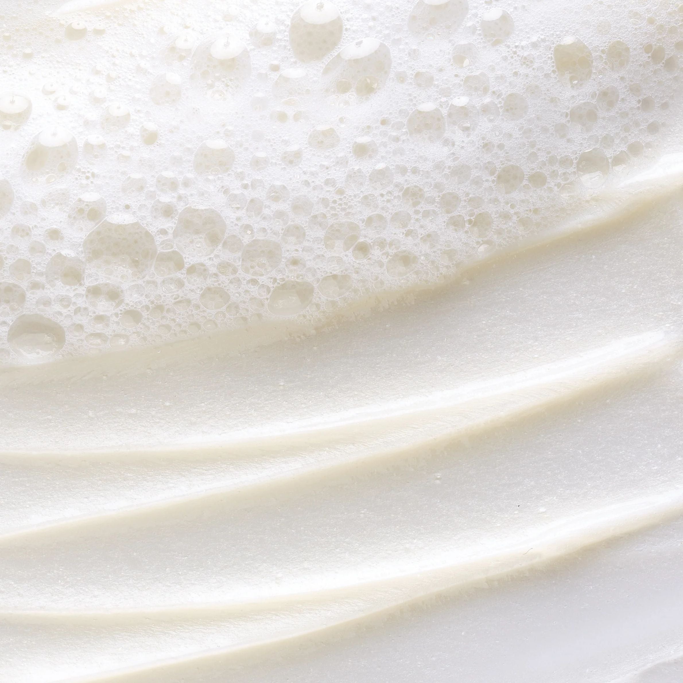 Close-up of white cream with bubbles on a white background